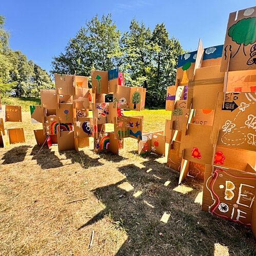 Cardboard structures covered in colourful drawings placed in a field