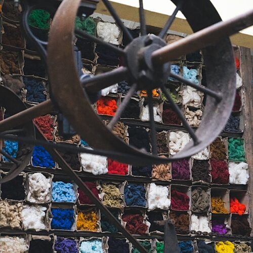 Squares of different coloured materials filling a wall as viewed through old mill machinery